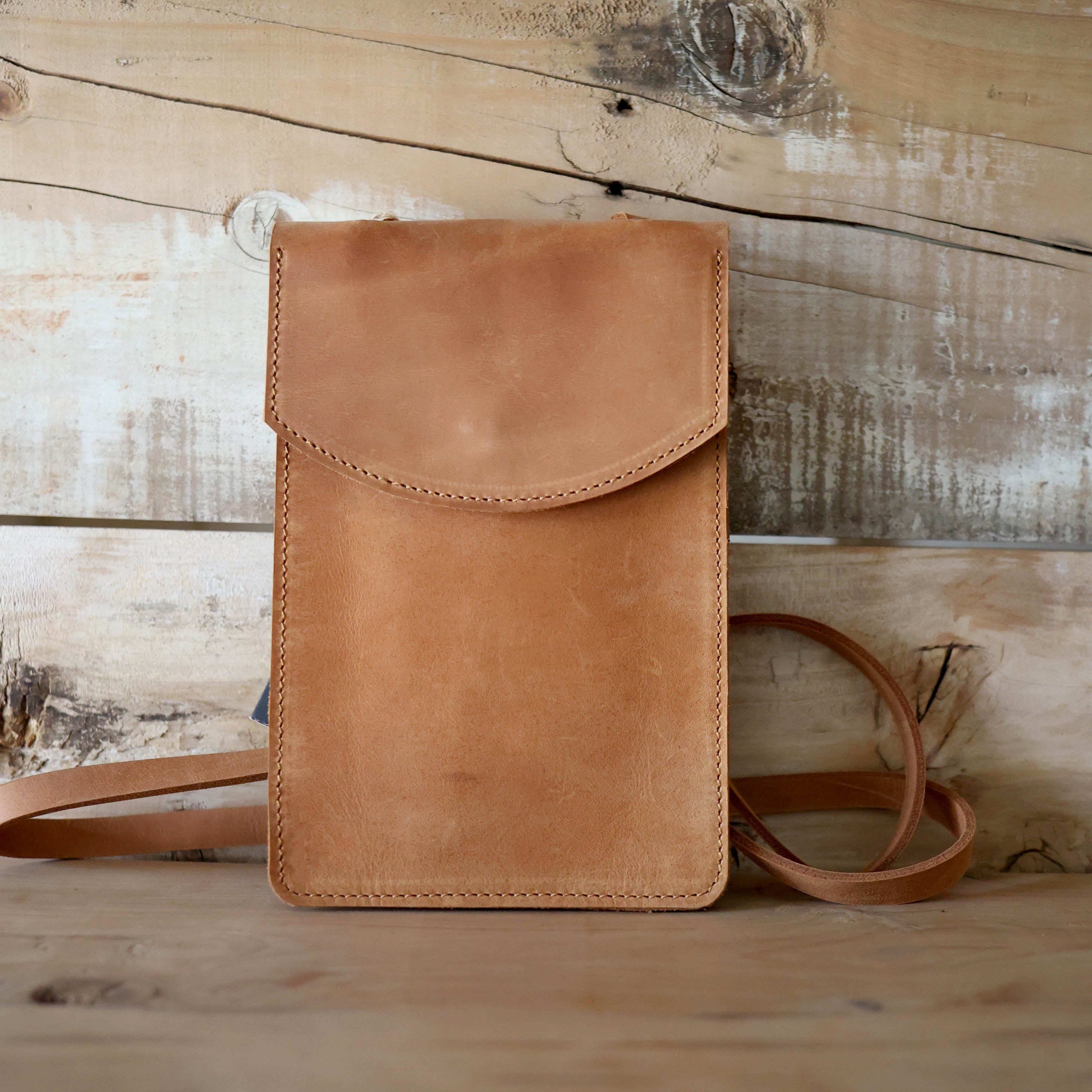 Brown leather crossbody bag on a wooden surface