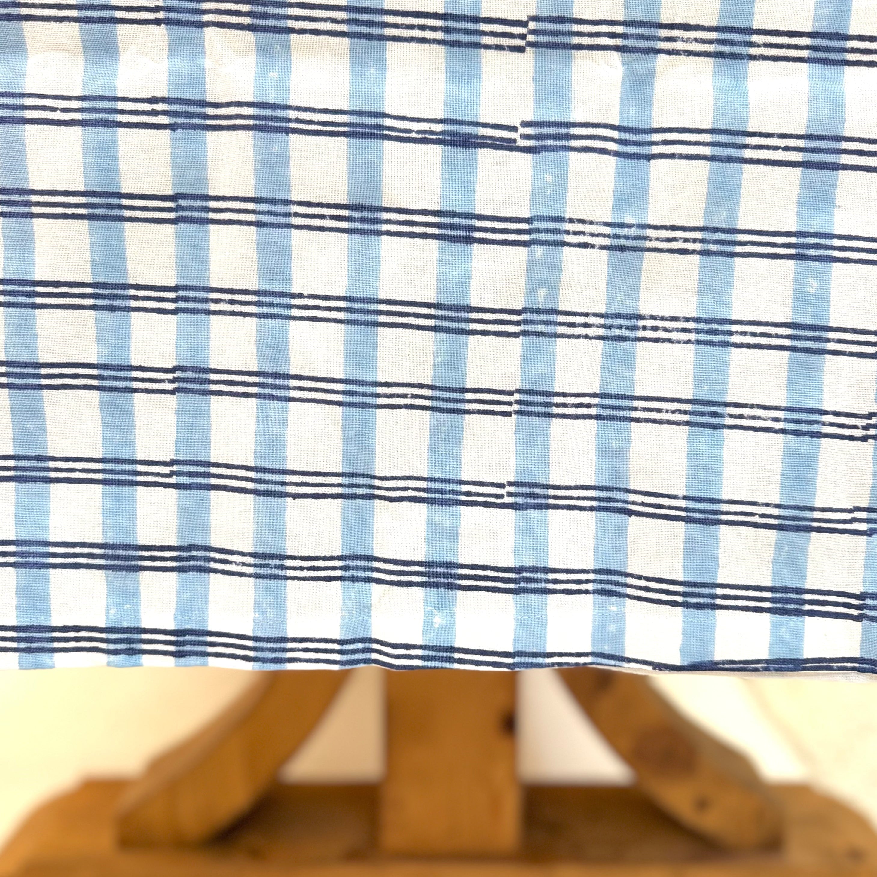 Close-up of a wooden sailboat model with a blue and white striped fabric background