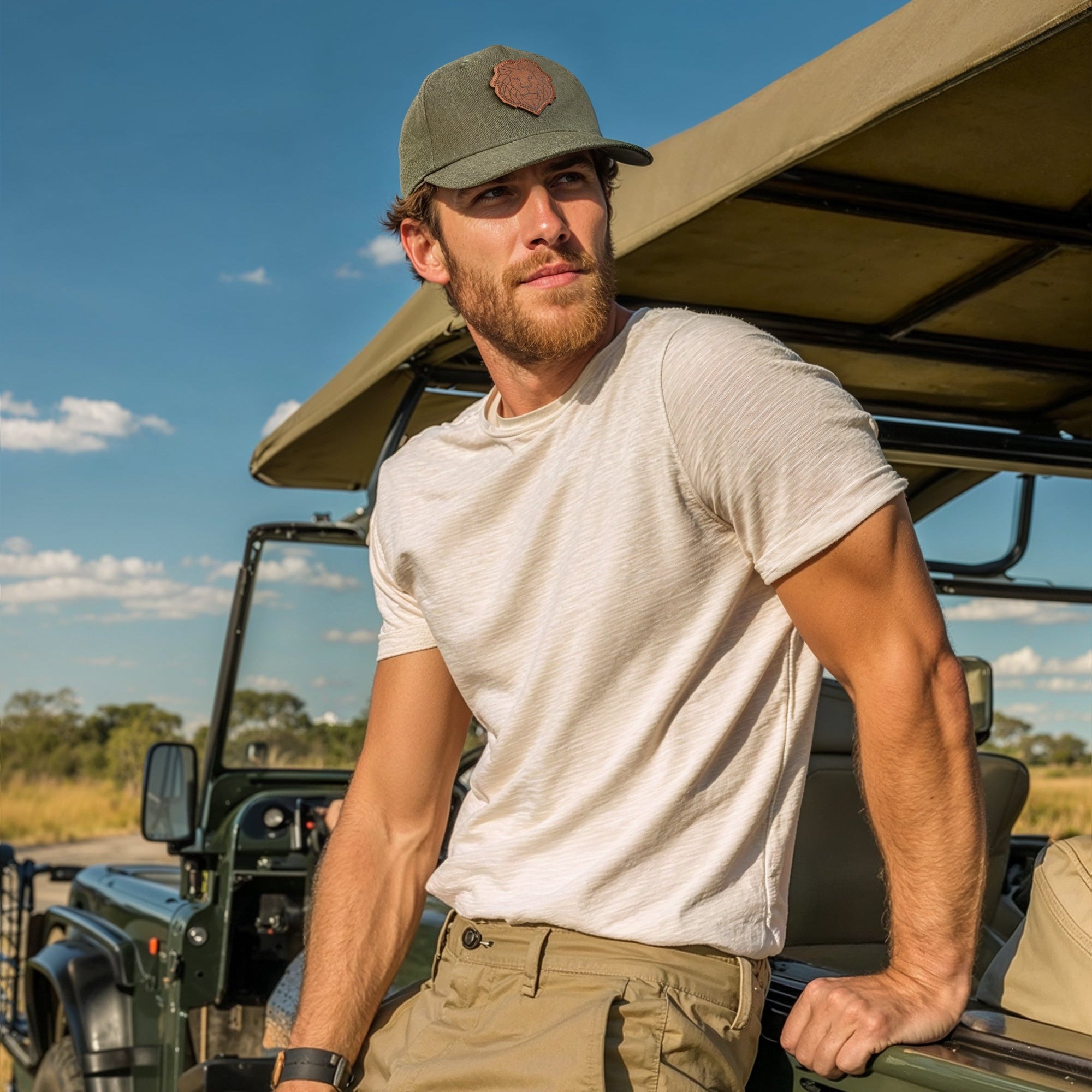Man standing next to a green safari vehicle in a grassy field