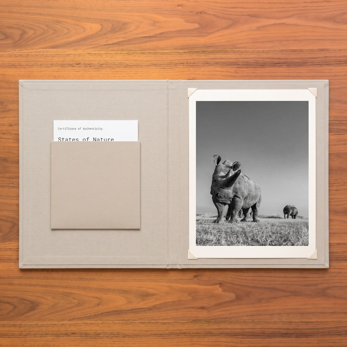 Archive Edition linen folio open to a Certificate of Authenticity and a print of Najin and Fatu, two rhinos on grassland