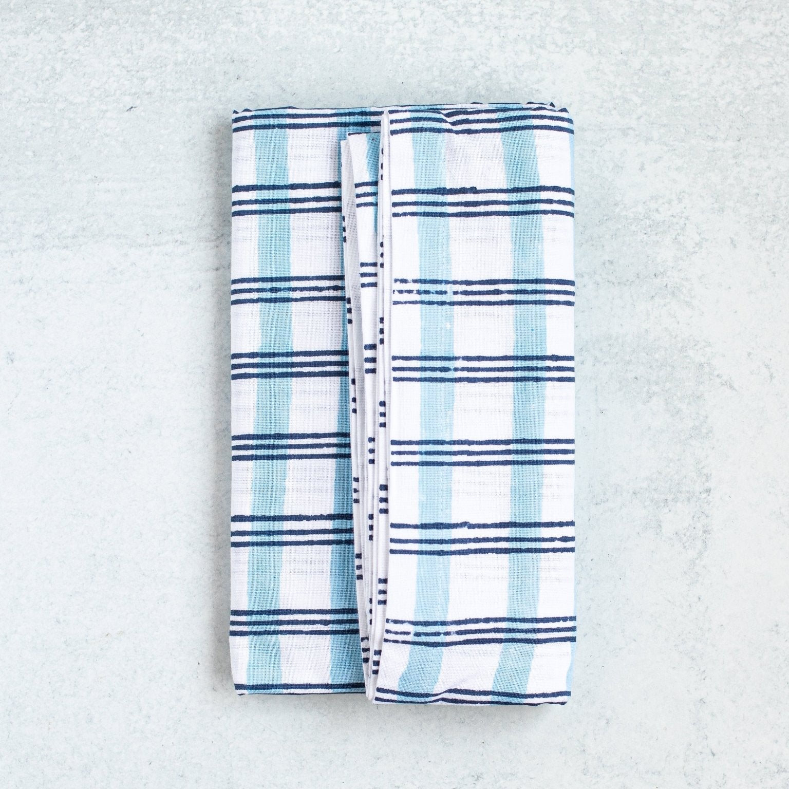 Folded blue and white checkered blanket on a textured gray surface