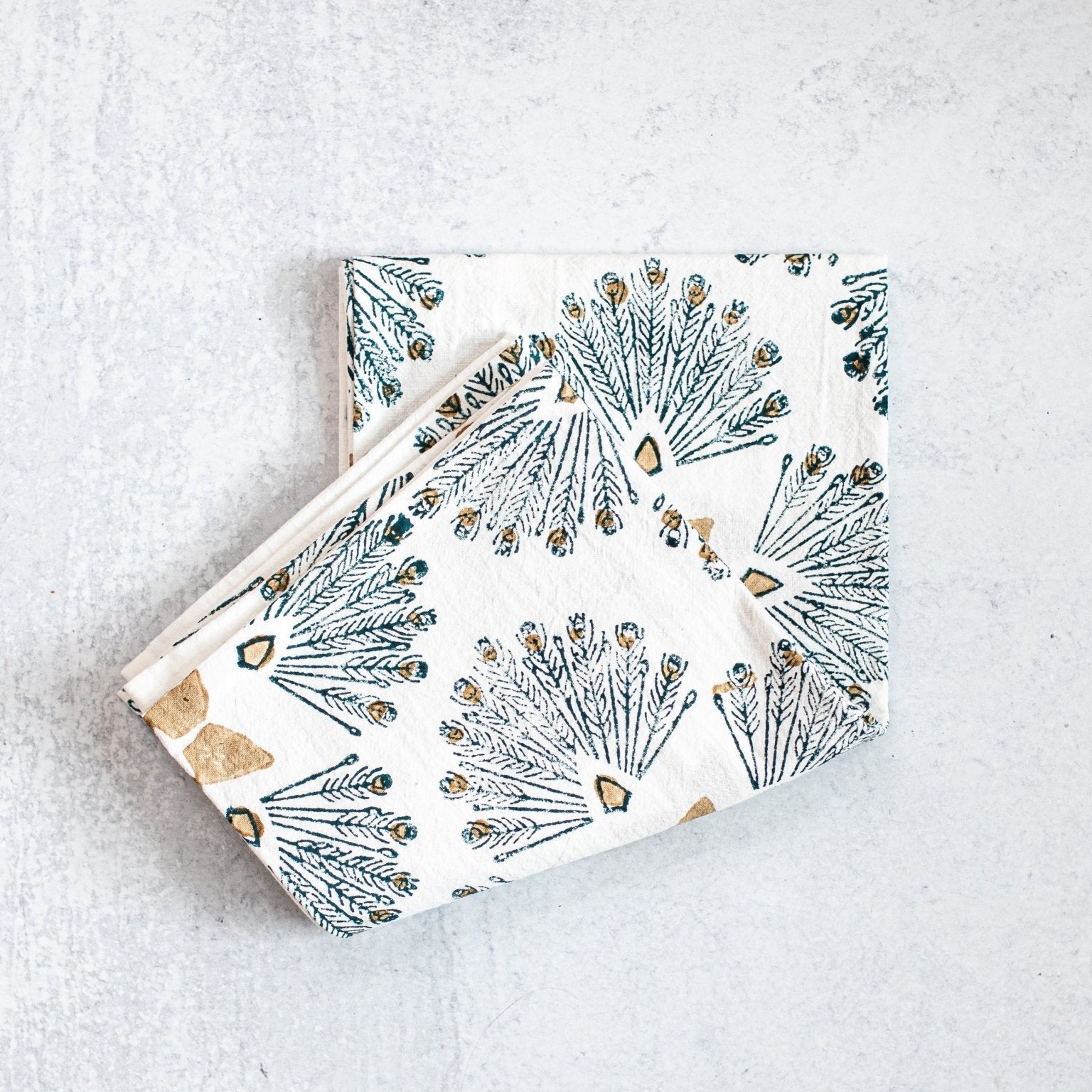 Two folded fabric napkins with geometric pattern on a light gray surface