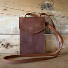 Brown leather crossbody bag on a wooden surface