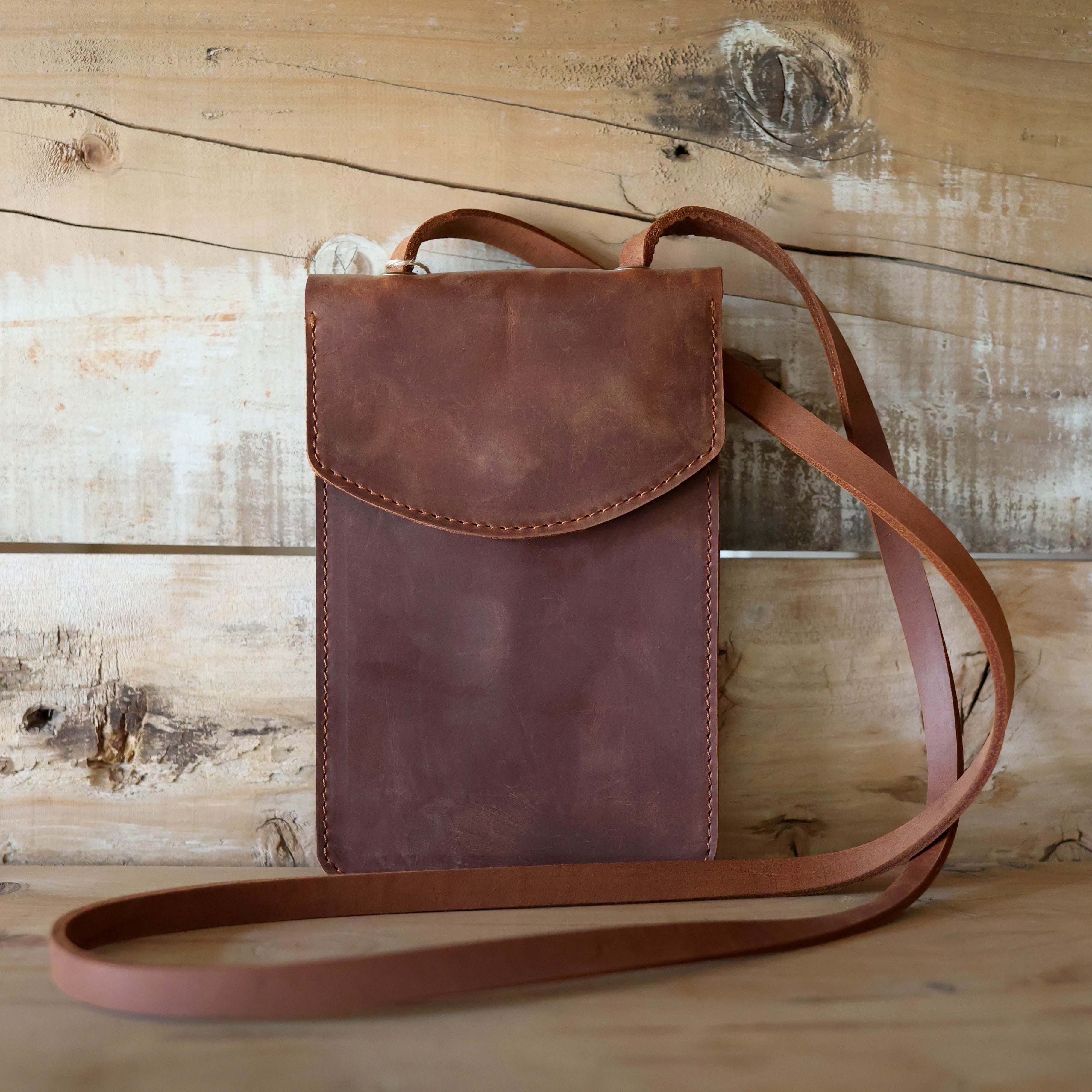 Brown leather crossbody bag on a wooden surface