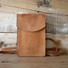 Brown leather crossbody bag on a wooden surface