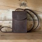Brown leather bag with a strap on a wooden surface