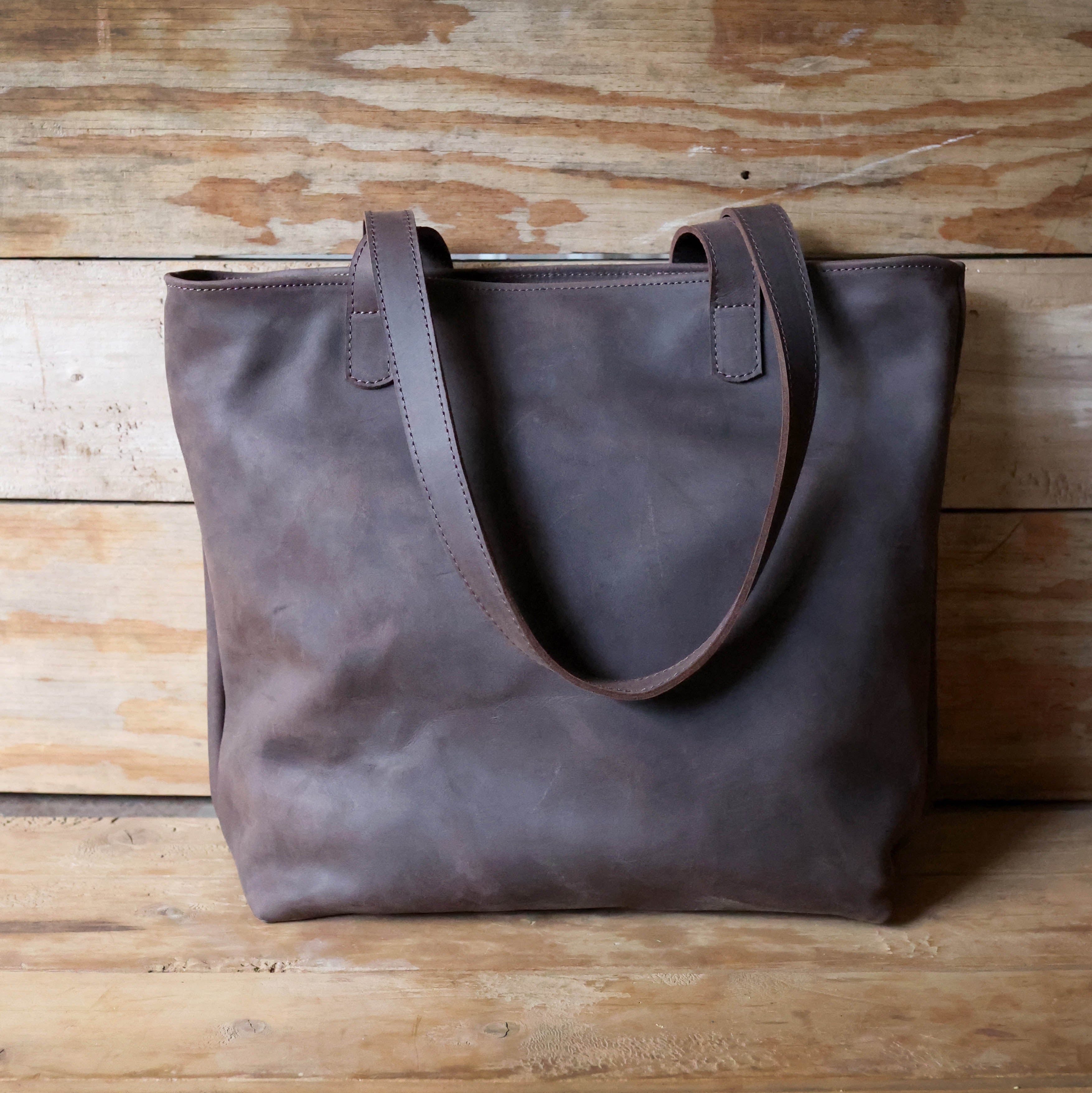 Brown leather tote bag on a wooden surface