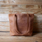 Brown leather tote bag on a wooden surface