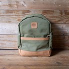Green backpack with brown accents on a wooden surface