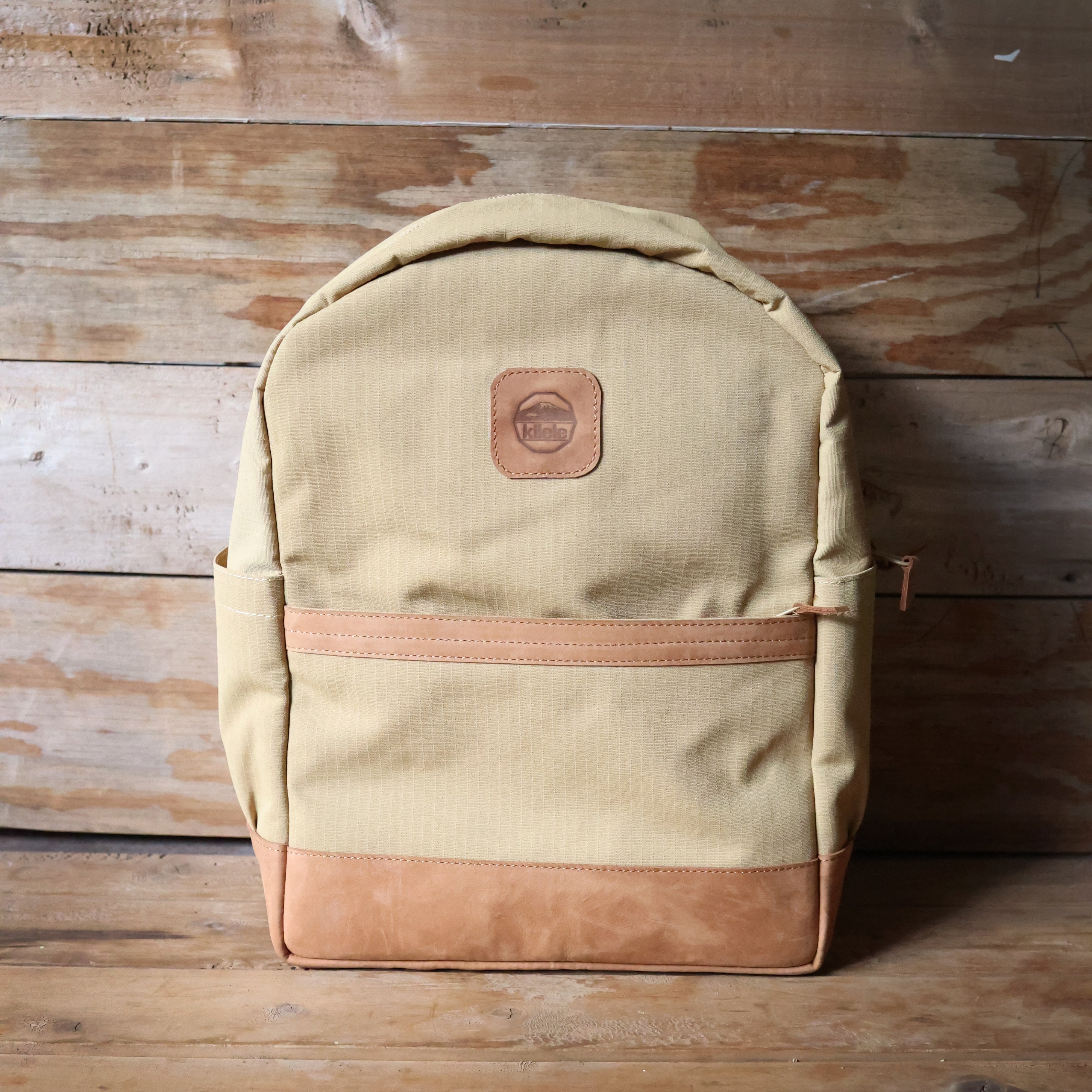 Beige backpack with brown accents on a wooden surface