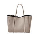 Beige woven handbag with black trim on a white background