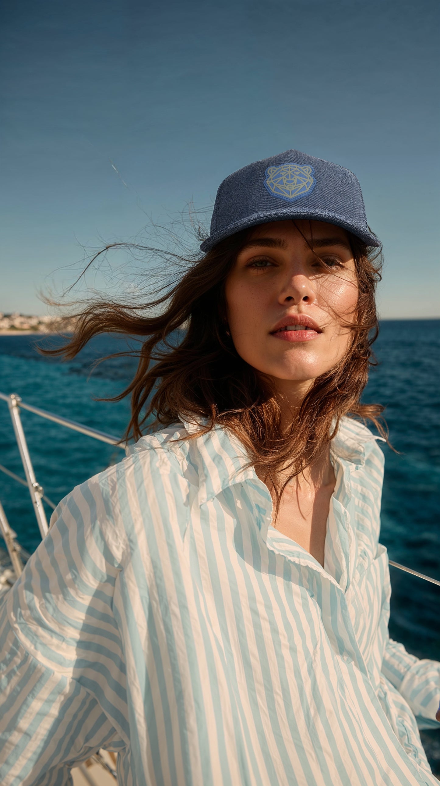 Woman wearing the Arctic Protector II cap and striped shirt on a boat with ocean and sky in the background