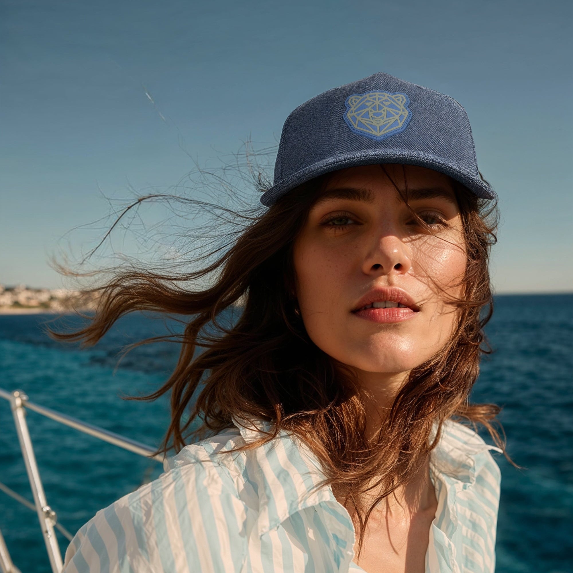Woman wearing the Arctic Protector II cap and striped shirt on a boat with ocean and sky in the background