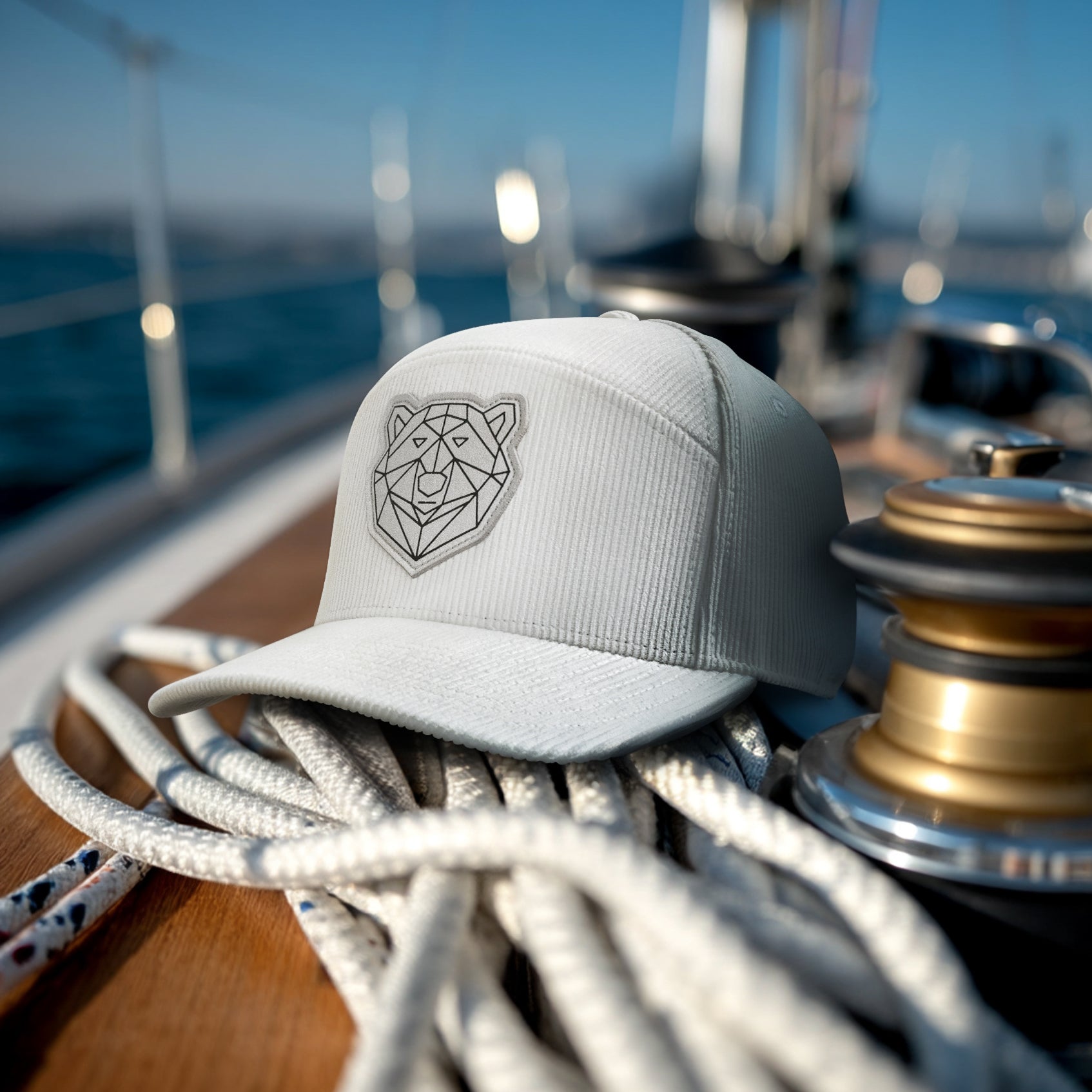 Gray cap with a geometric bear design on a boat with ropes and metal parts.