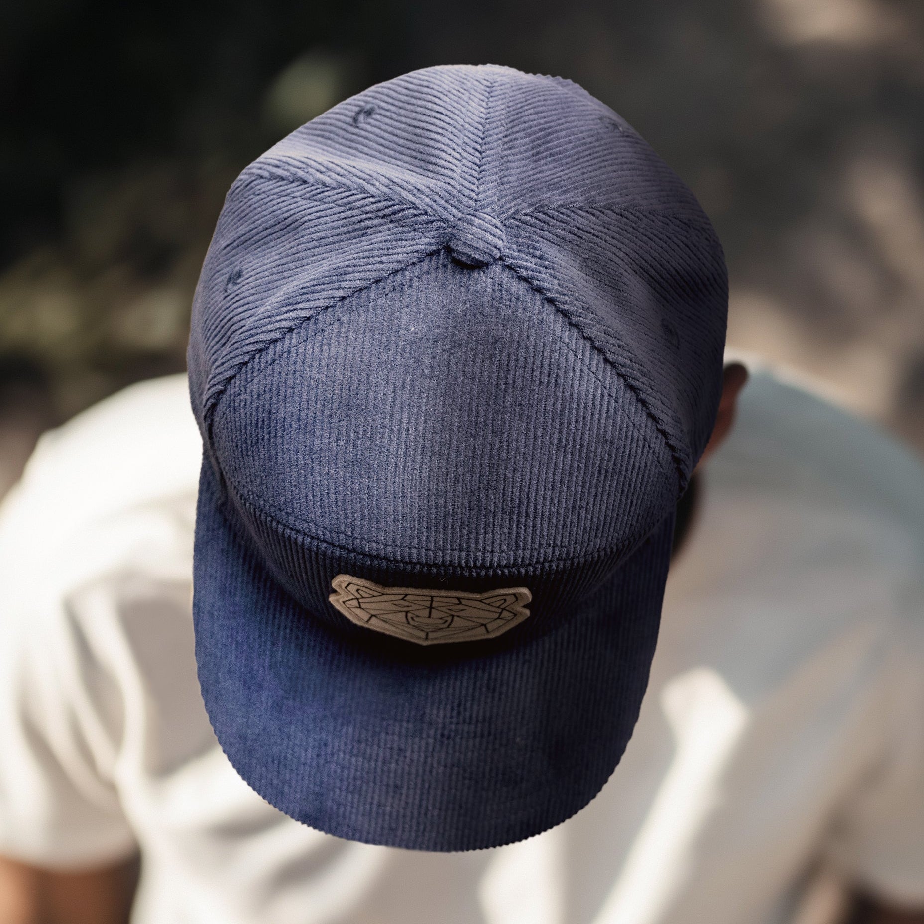 Two caps, one blue and one beige, with a geometric pattern of a polar bear face on them, displayed on a neutral background.