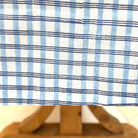 Close-up of a wooden sailboat model with a blue and white striped fabric background