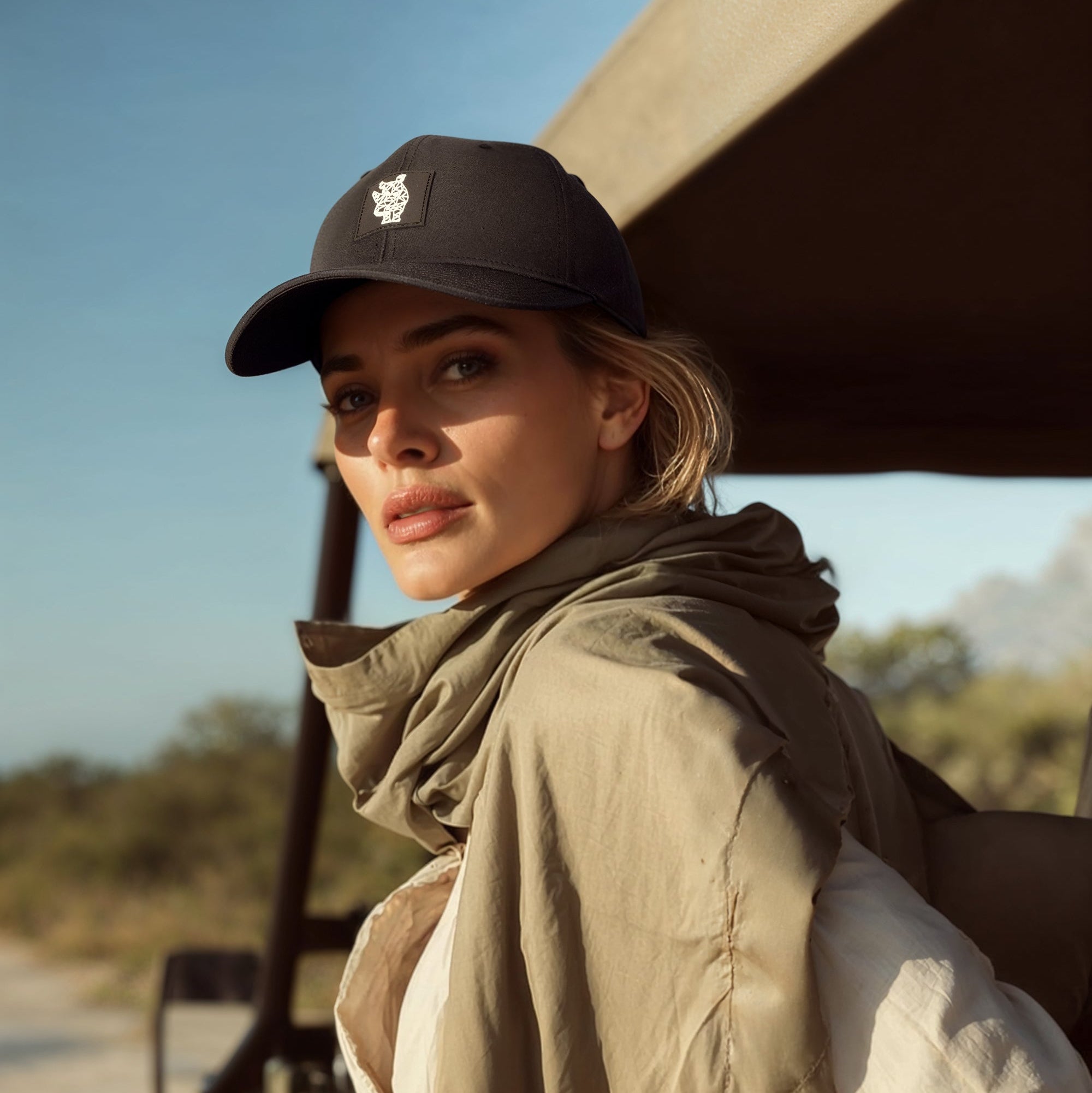 Woman wearing a black cap and beige jacket in an outdoor setting