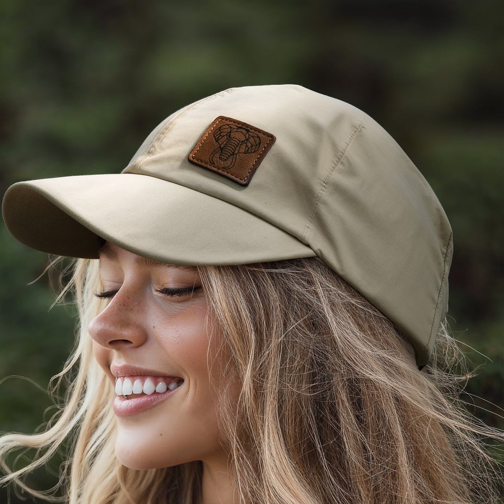 A green baseball cap with a leather patch on the front, placed on a rock with a blurred natural background.