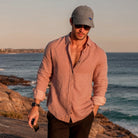 Man walking along a rocky coastal path with ocean in the background