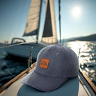 Blue cap with a leather patch on a boat with a sail in the background