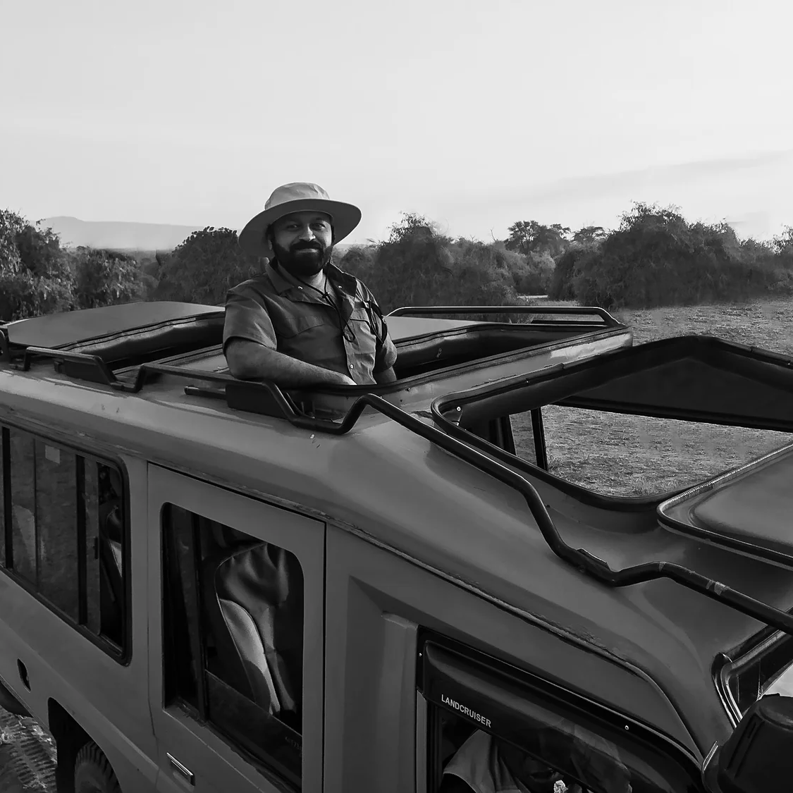 Man sitting on a vehicle with open roof racks in a natural setting