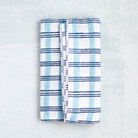 Folded blue and white checkered blanket on a textured gray surface