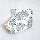 Two folded fabric napkins with geometric pattern on a light gray surface