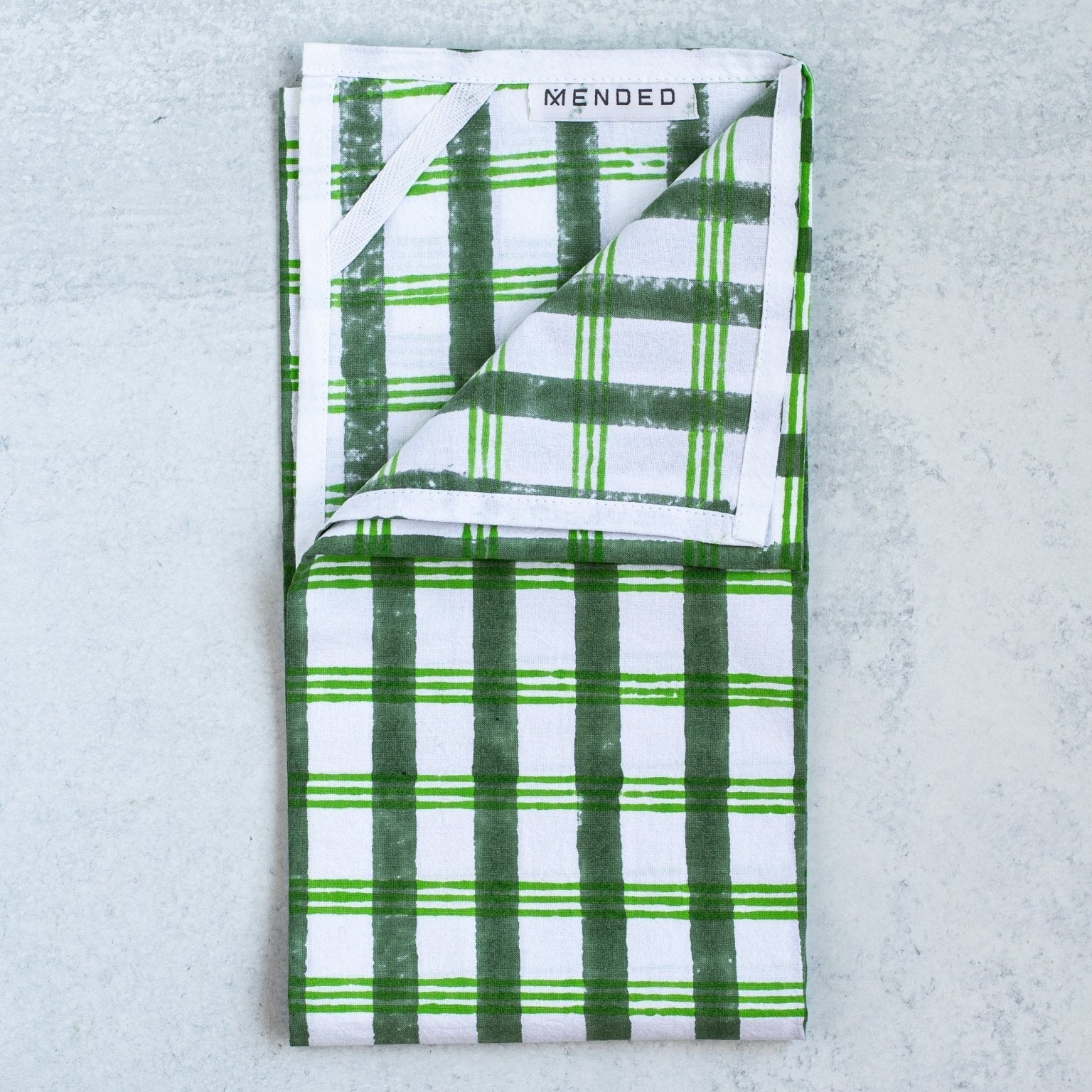 Folded green and white checkered towel with 'WENDEO' branding on a light gray background